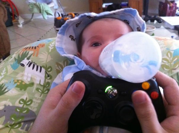 Bébé boit biberon posé sur manette Xbox