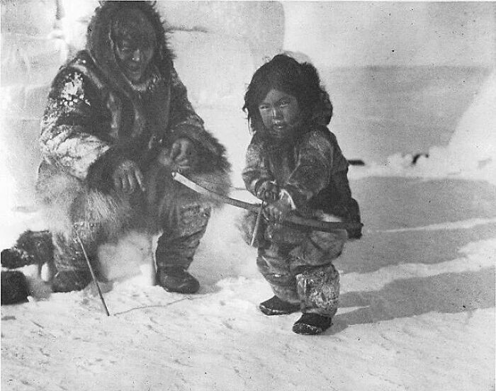 Inuit man and his son learning to shoot